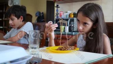 小女孩不情愿地用叉子吃<strong>荞麦</strong>面。 这孩子拒绝吃饭。 慢镜头拍摄。